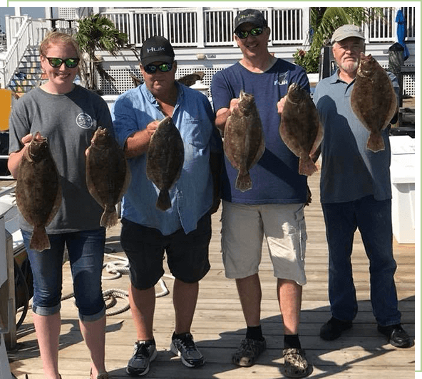 A group of people holding fish on the dock.